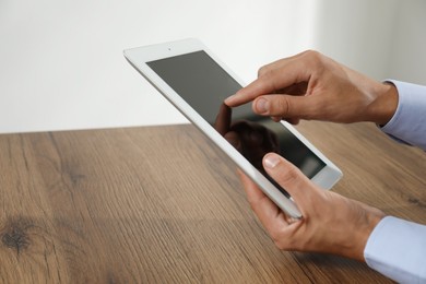 Photo of Businessman using tablet at wooden table, closeup. Modern technology