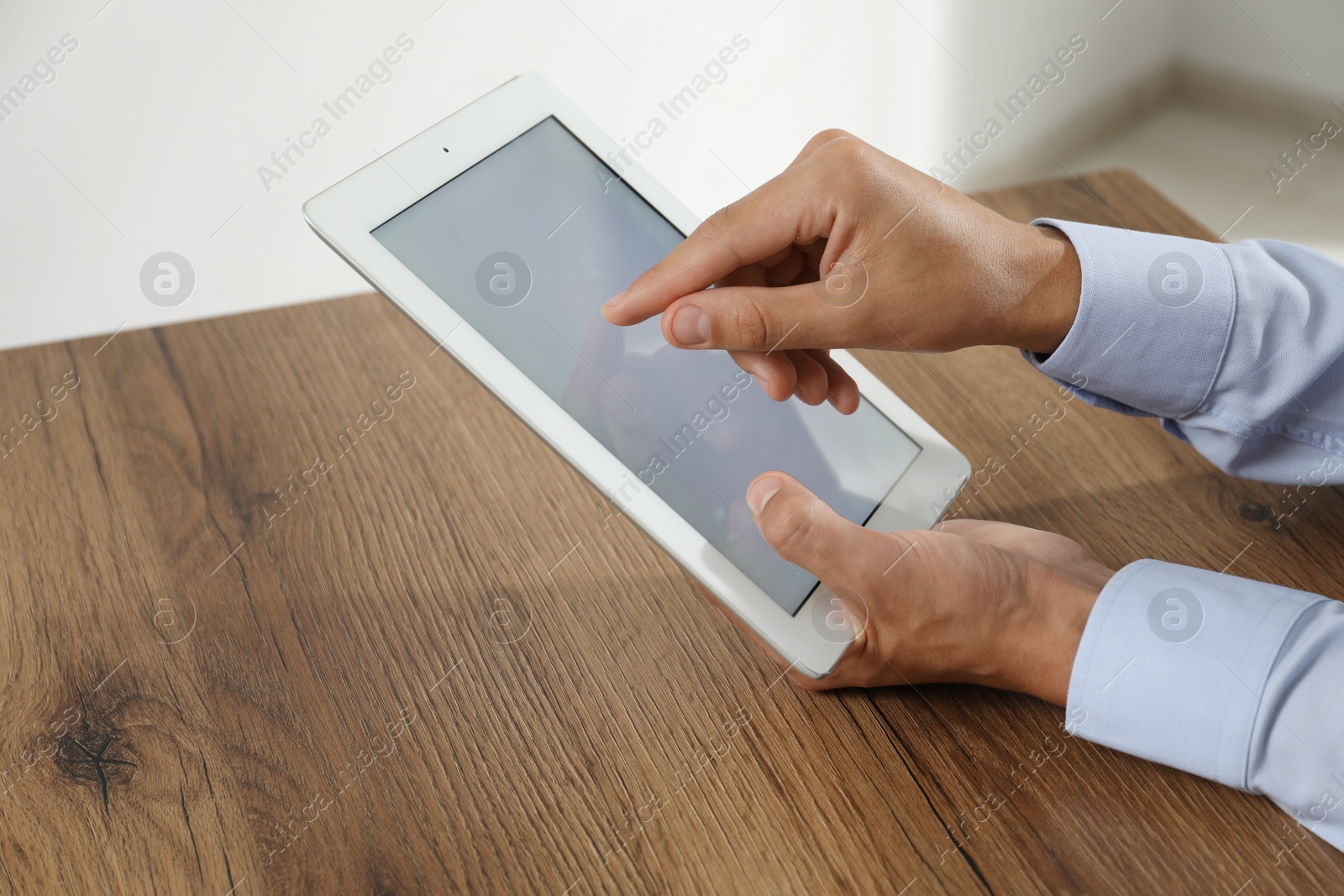 Photo of Businessman using tablet at wooden table, closeup. Modern technology