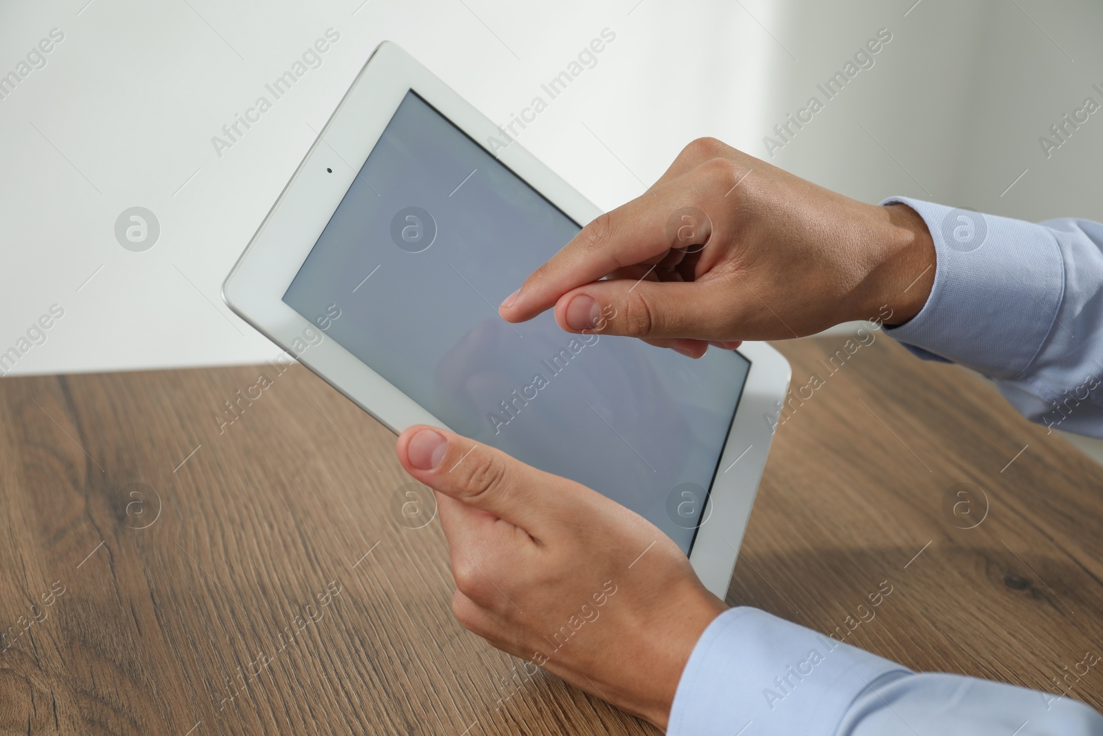 Photo of Businessman using tablet at wooden table, closeup. Modern technology