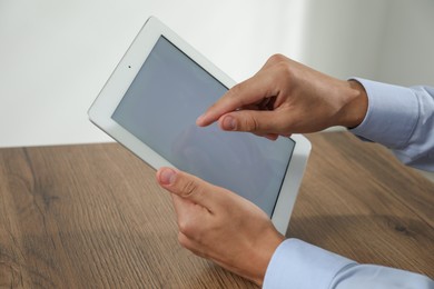 Photo of Businessman using tablet at wooden table, closeup. Modern technology