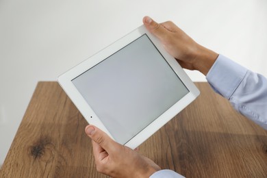 Photo of Businessman using tablet at wooden table, closeup. Modern technology