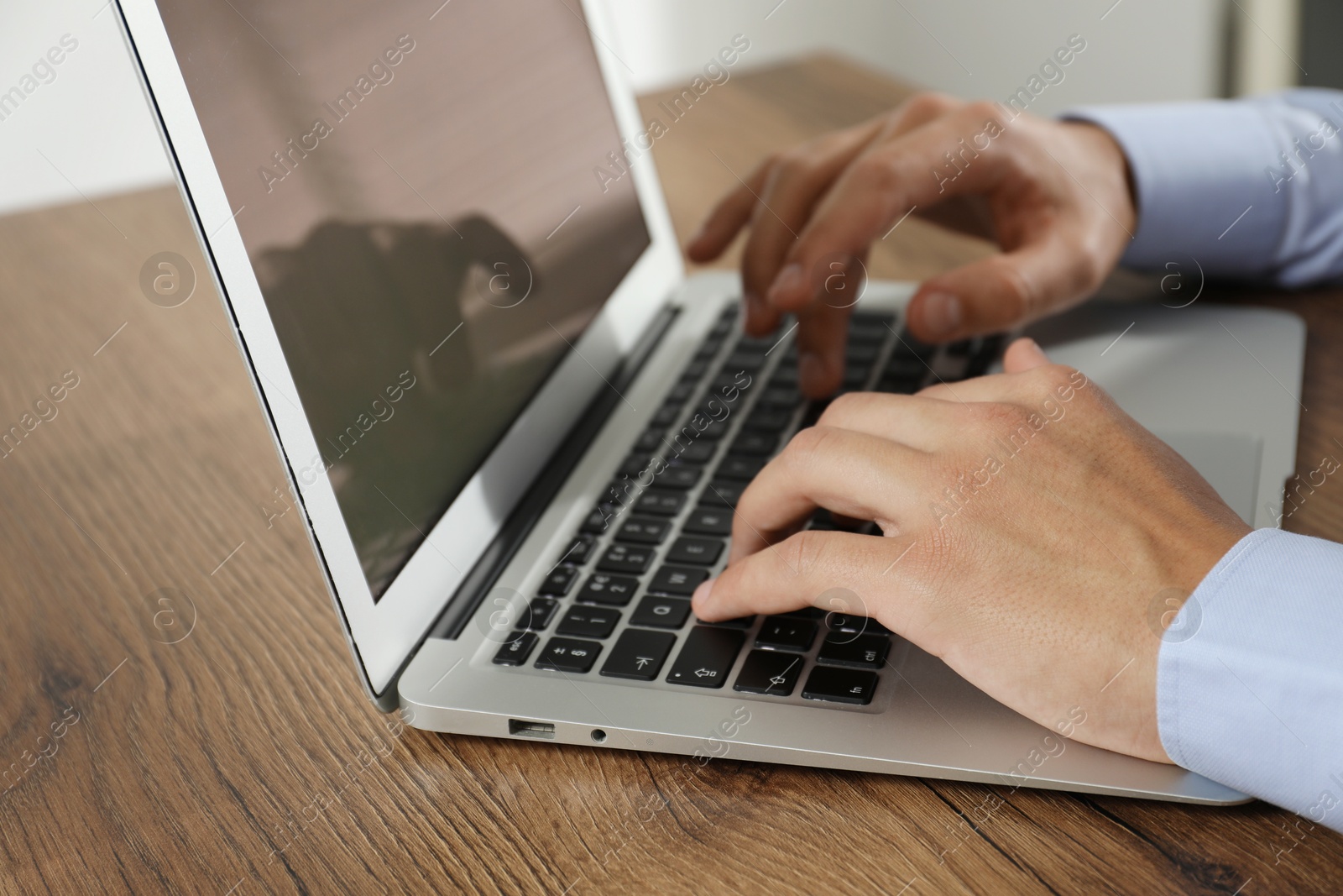 Photo of Businessman using laptop at wooden table, closeup. Modern technology