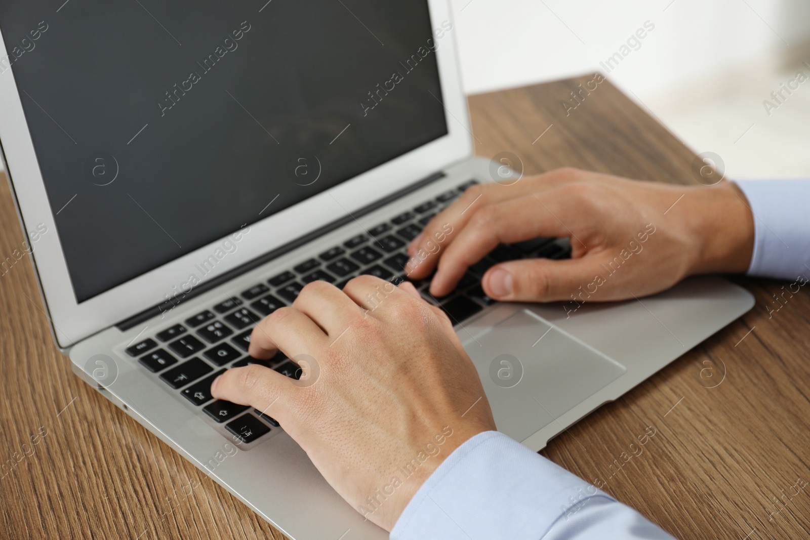 Photo of Businessman using laptop at wooden table, closeup. Modern technology