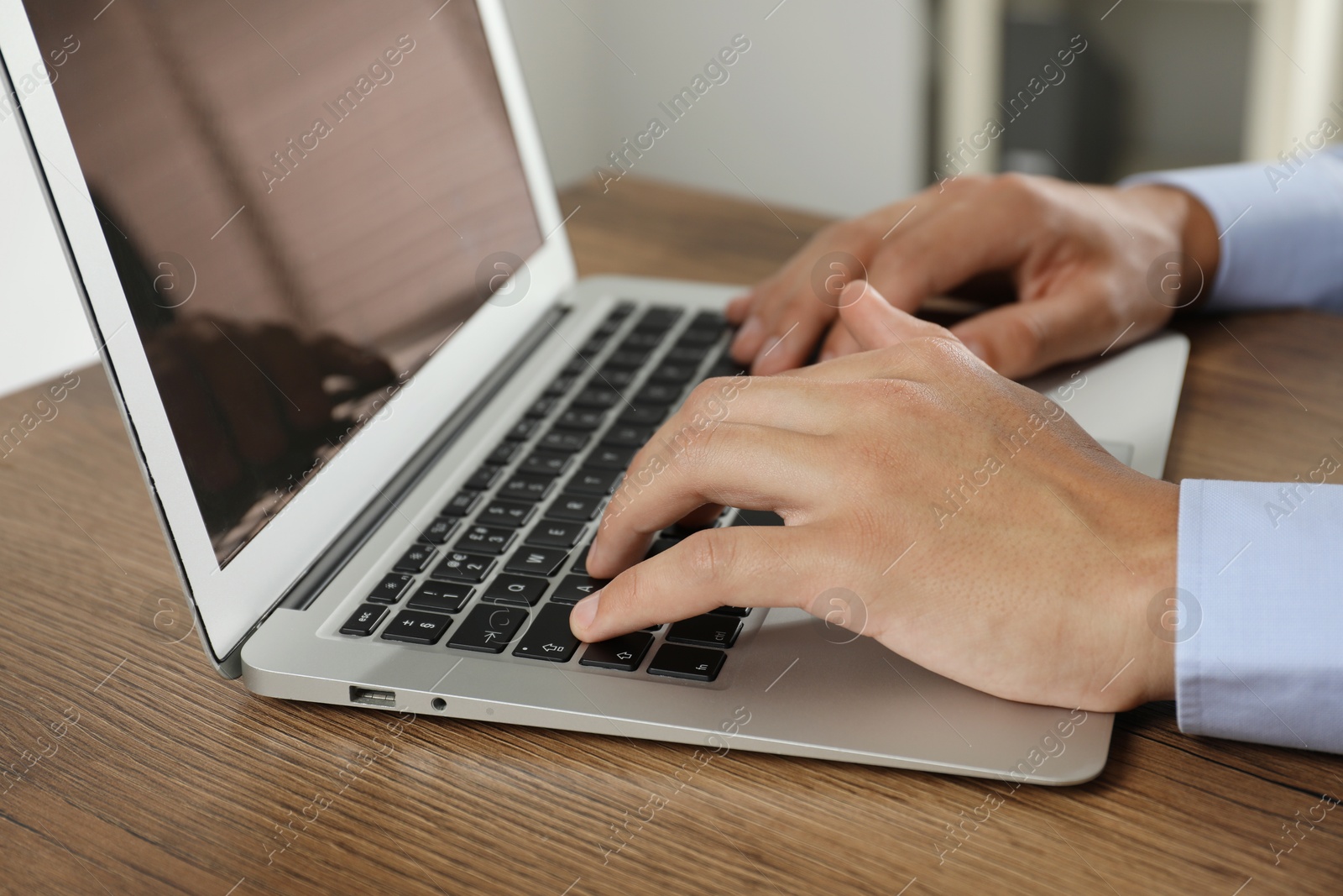 Photo of Businessman using laptop at wooden table, closeup. Modern technology