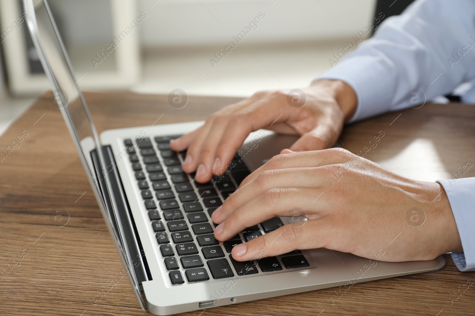 Photo of Businessman using laptop at wooden table, closeup. Modern technology