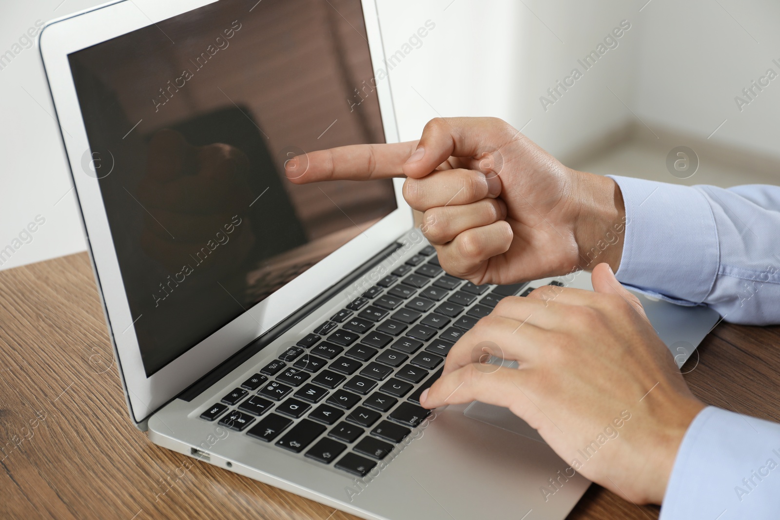 Photo of Businessman using laptop at wooden table, closeup. Modern technology