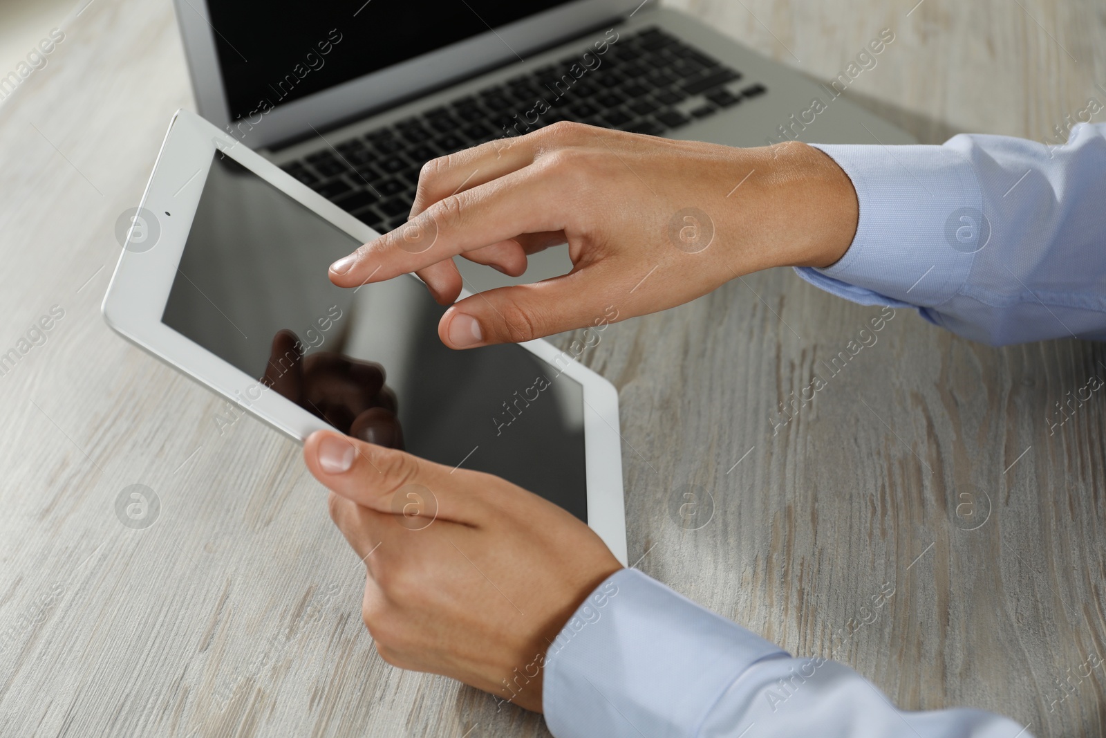 Photo of Businessman with tablet and laptop at wooden table, closeup. Modern technology