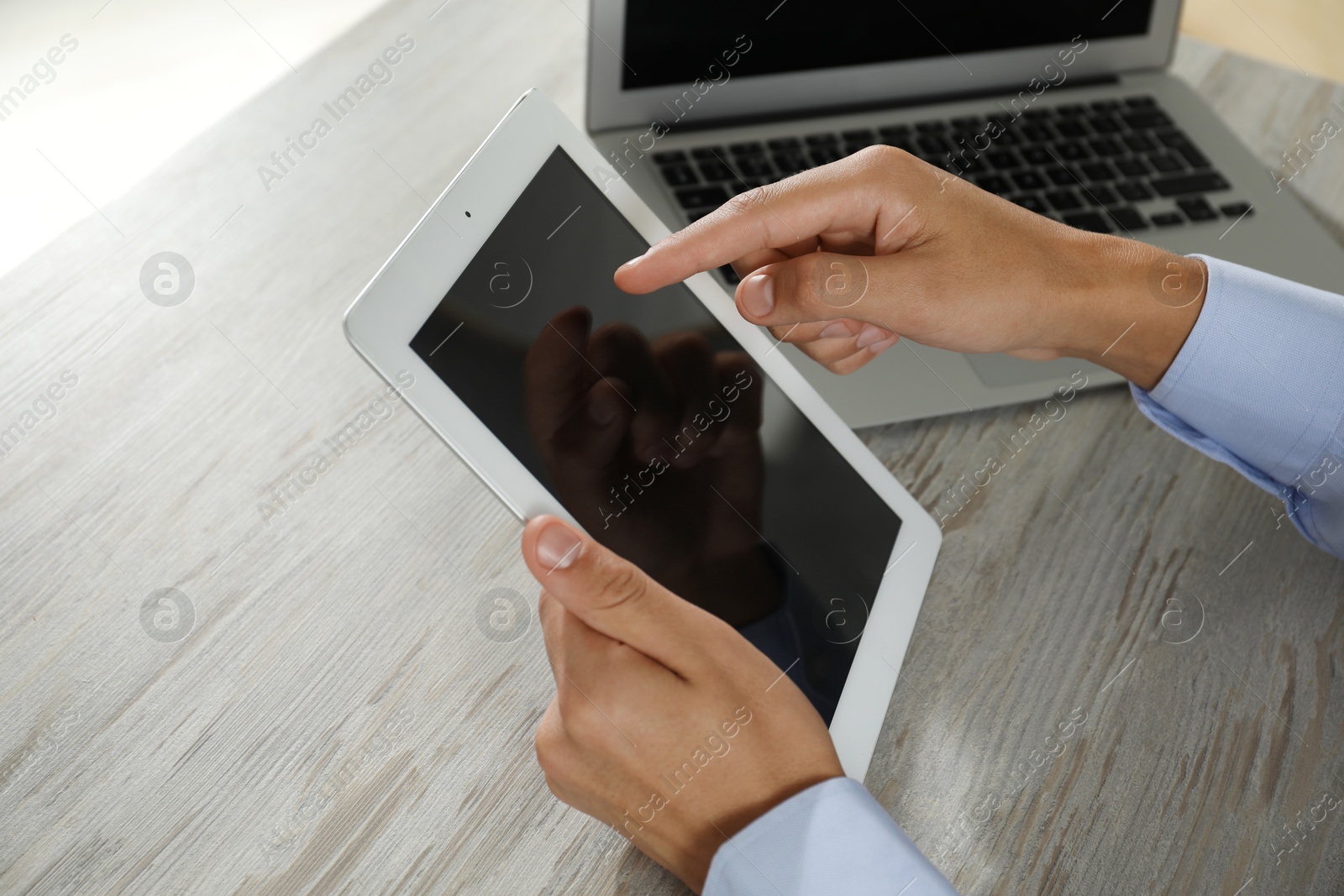 Photo of Businessman with tablet and laptop at wooden table, closeup. Modern technology