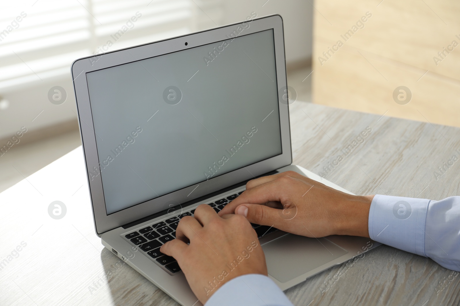 Photo of Businessman using laptop at wooden table, closeup. Modern technology