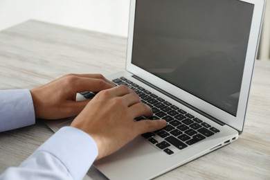 Photo of Businessman using laptop at wooden table, closeup. Modern technology