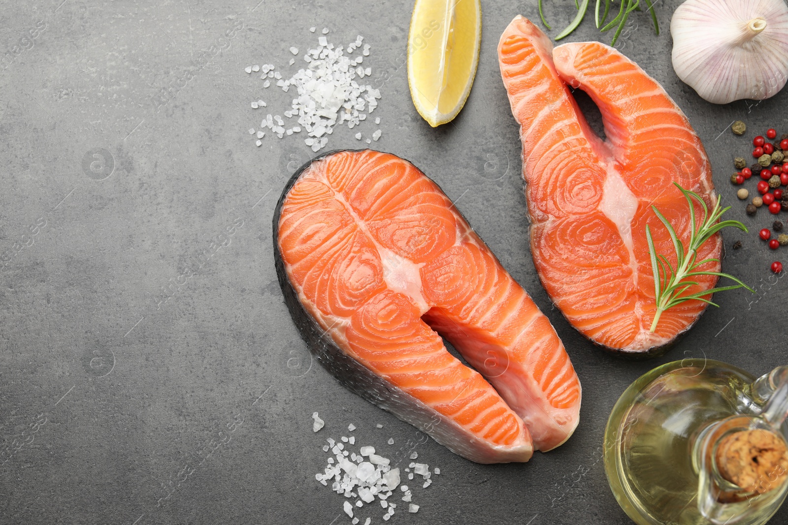 Photo of Fresh raw salmon steaks and spices on grey textured table, flat lay. Space for text