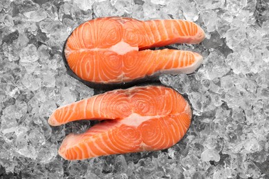 Photo of Fresh raw salmon steaks on ice pieces, top view