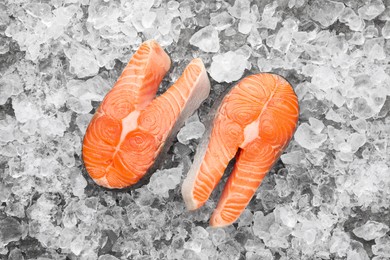 Photo of Fresh raw salmon steaks on ice pieces, top view