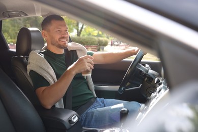 Man with cup of coffee driving modern car