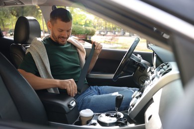 Photo of Man fastening seat belt in modern car