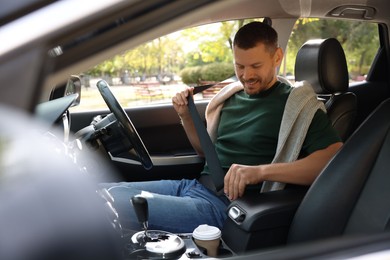 Photo of Man fastening seat belt in modern car