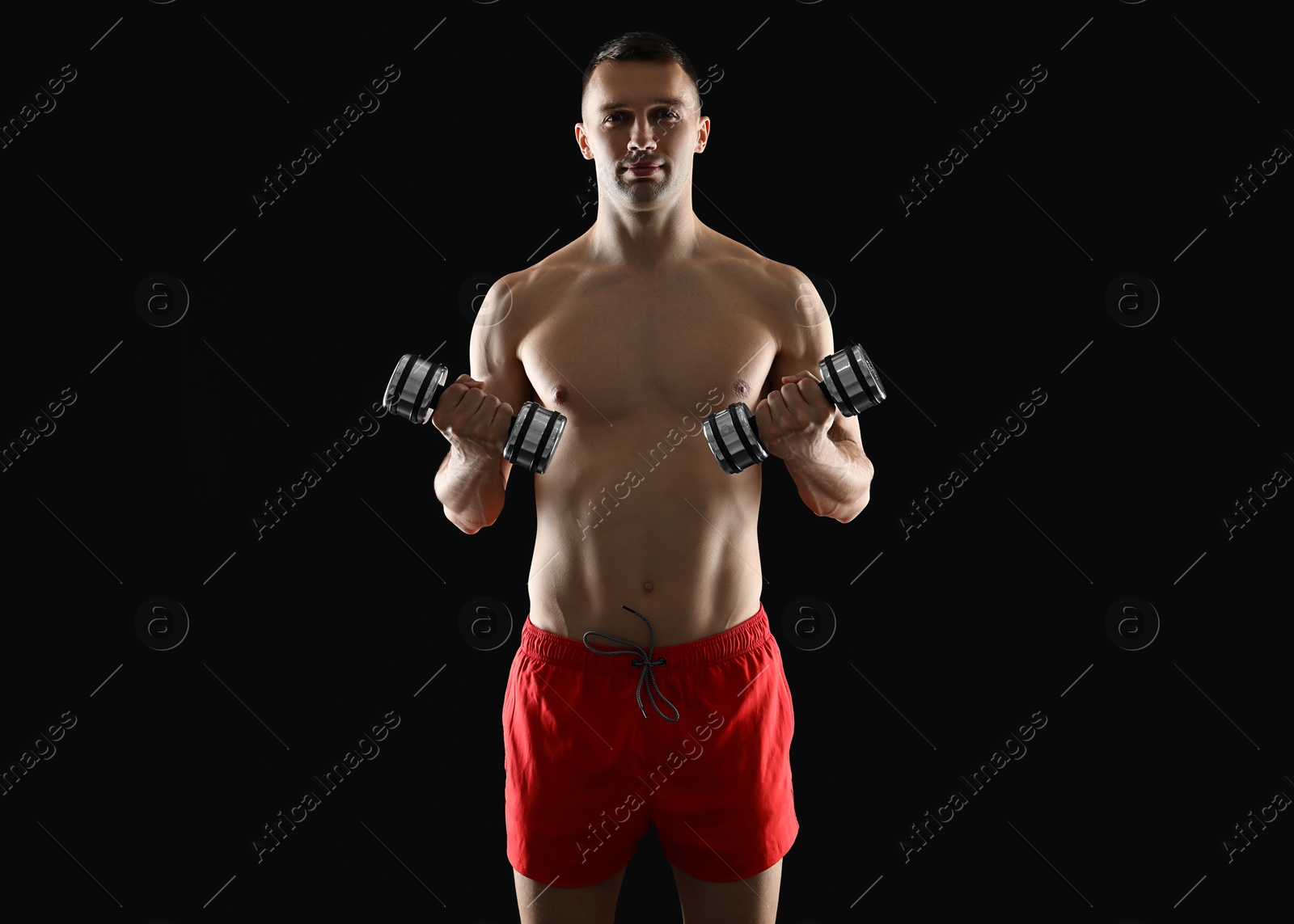 Photo of Man exercising with dumbbells on black background