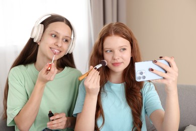 Photo of Teenage girls applying makeup products and taking selfie indoors