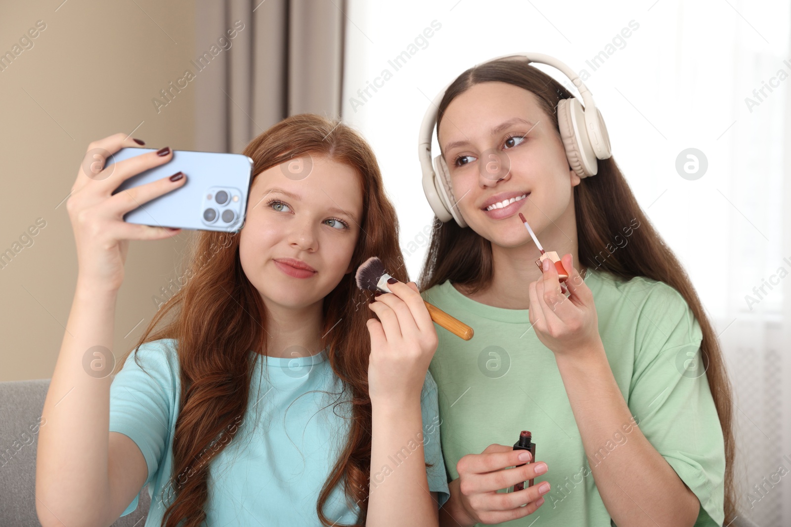 Photo of Teenage girls applying makeup products and taking selfie indoors