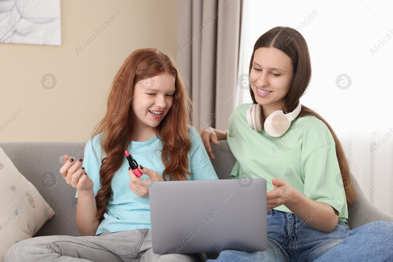 Photo of Teenage girls with laptop applying makeup products indoors