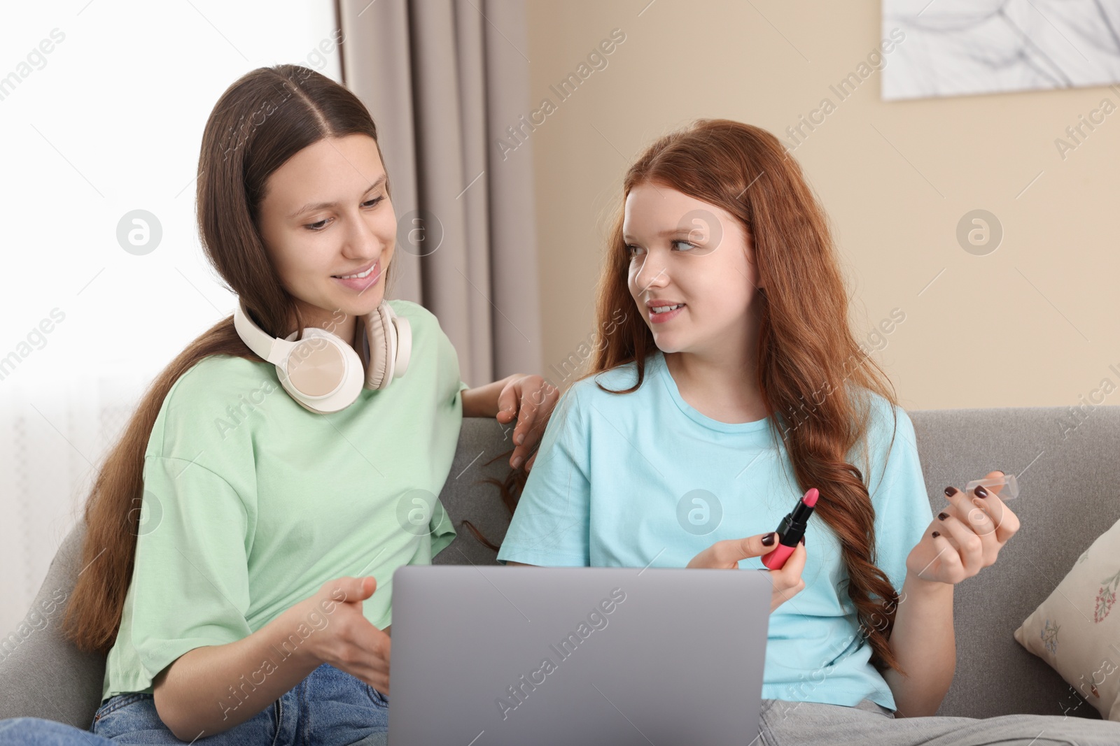 Photo of Teenage girls with laptop applying makeup products indoors