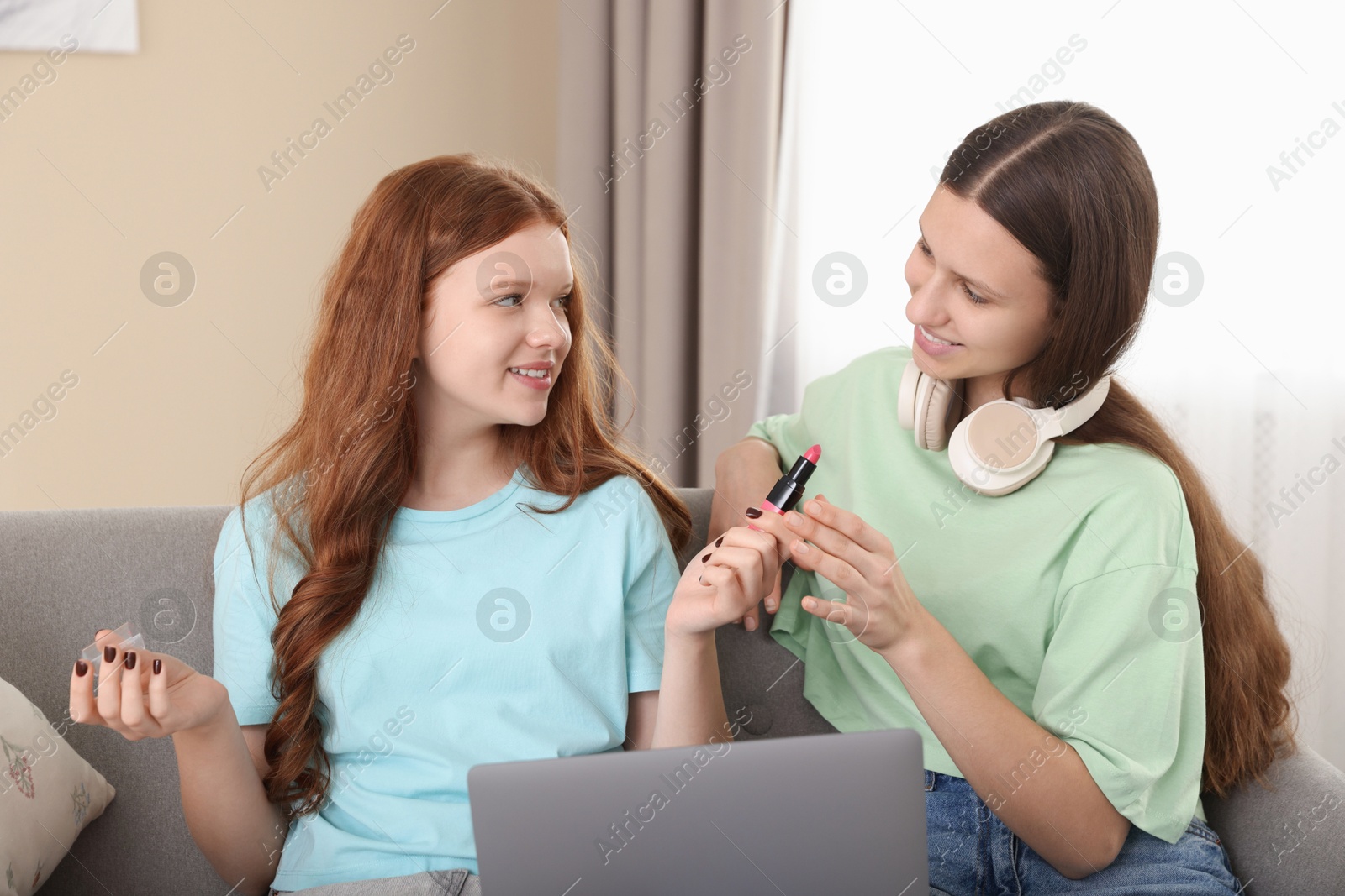 Photo of Teenage girls with laptop applying makeup products indoors