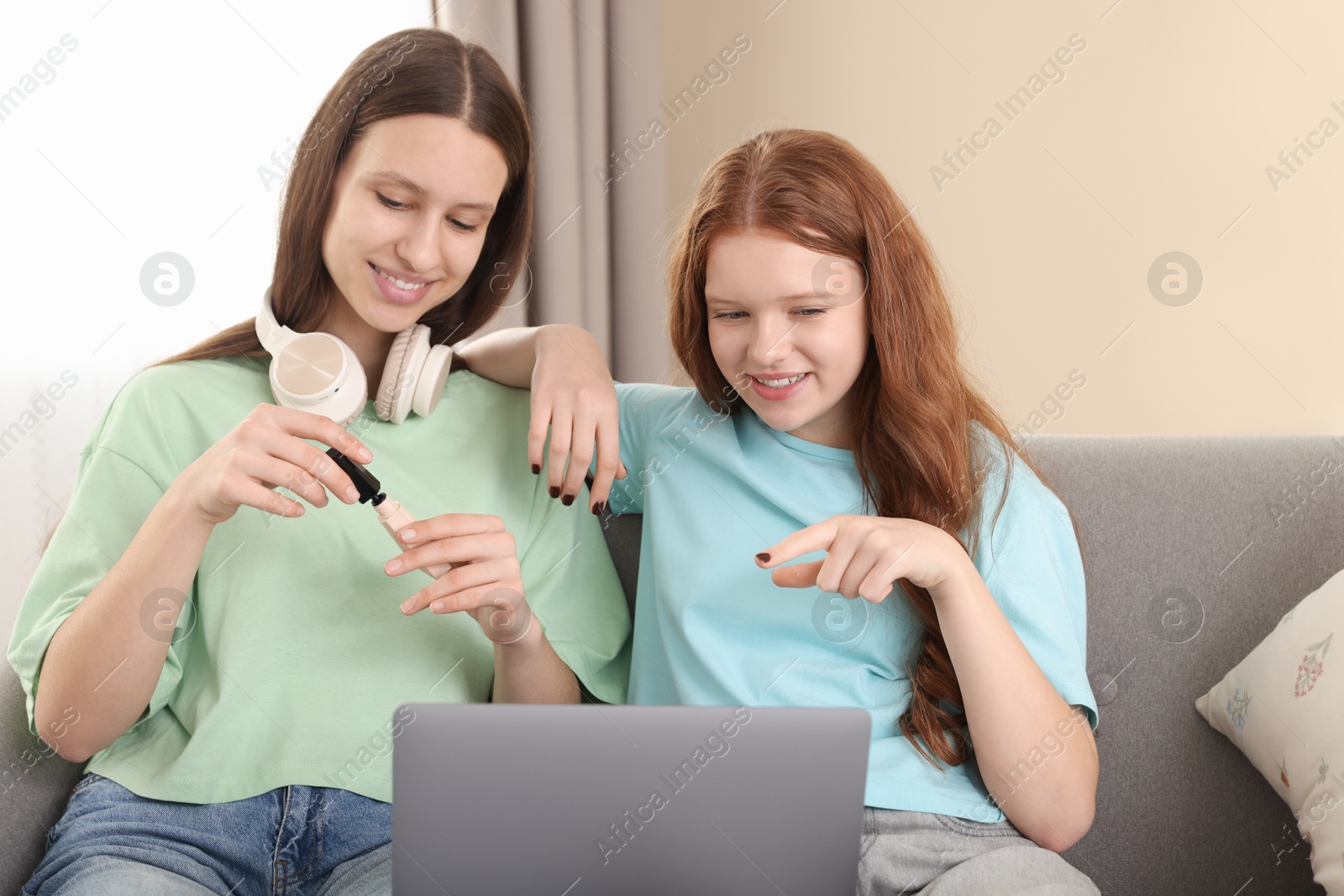 Photo of Teenage girls with laptop applying makeup products indoors