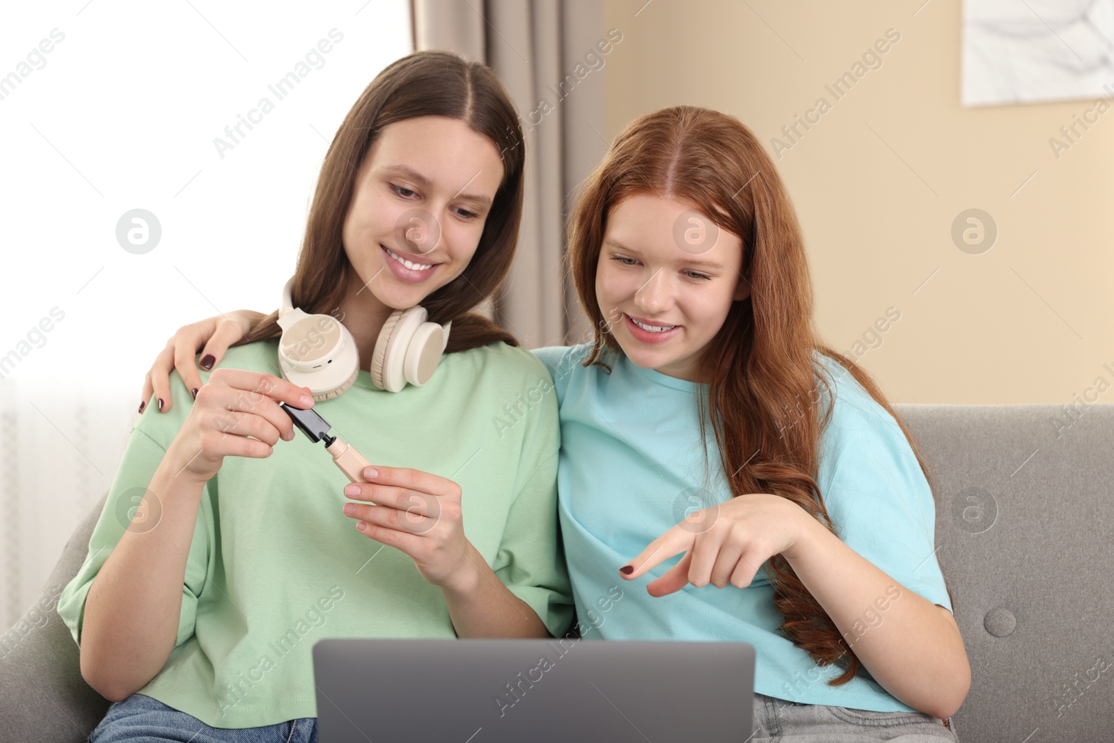 Photo of Teenage girls with laptop applying makeup products indoors