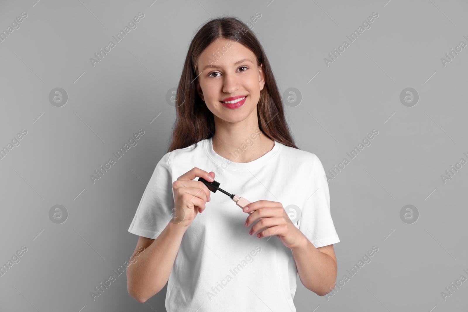 Photo of Smiling teenage girl with mascara on grey background