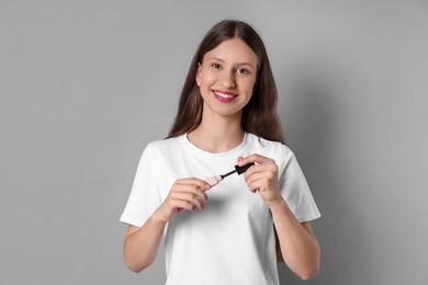 Photo of Smiling teenage girl with mascara on grey background