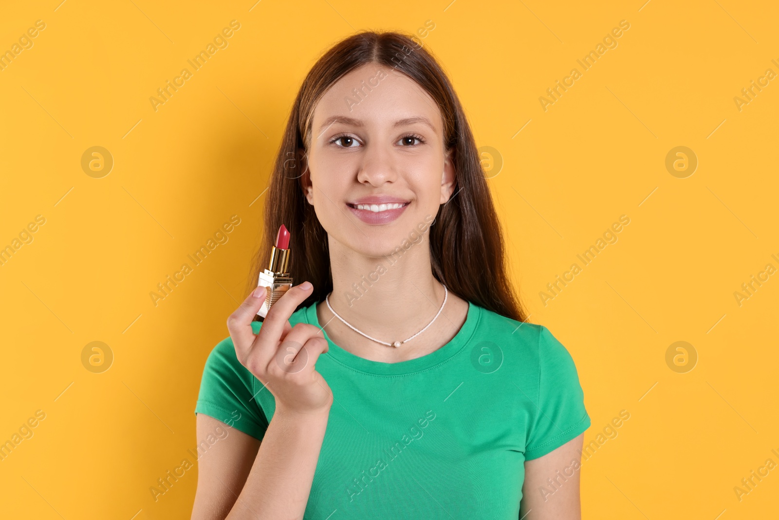 Photo of Smiling teenage girl with lipstick on yellow background