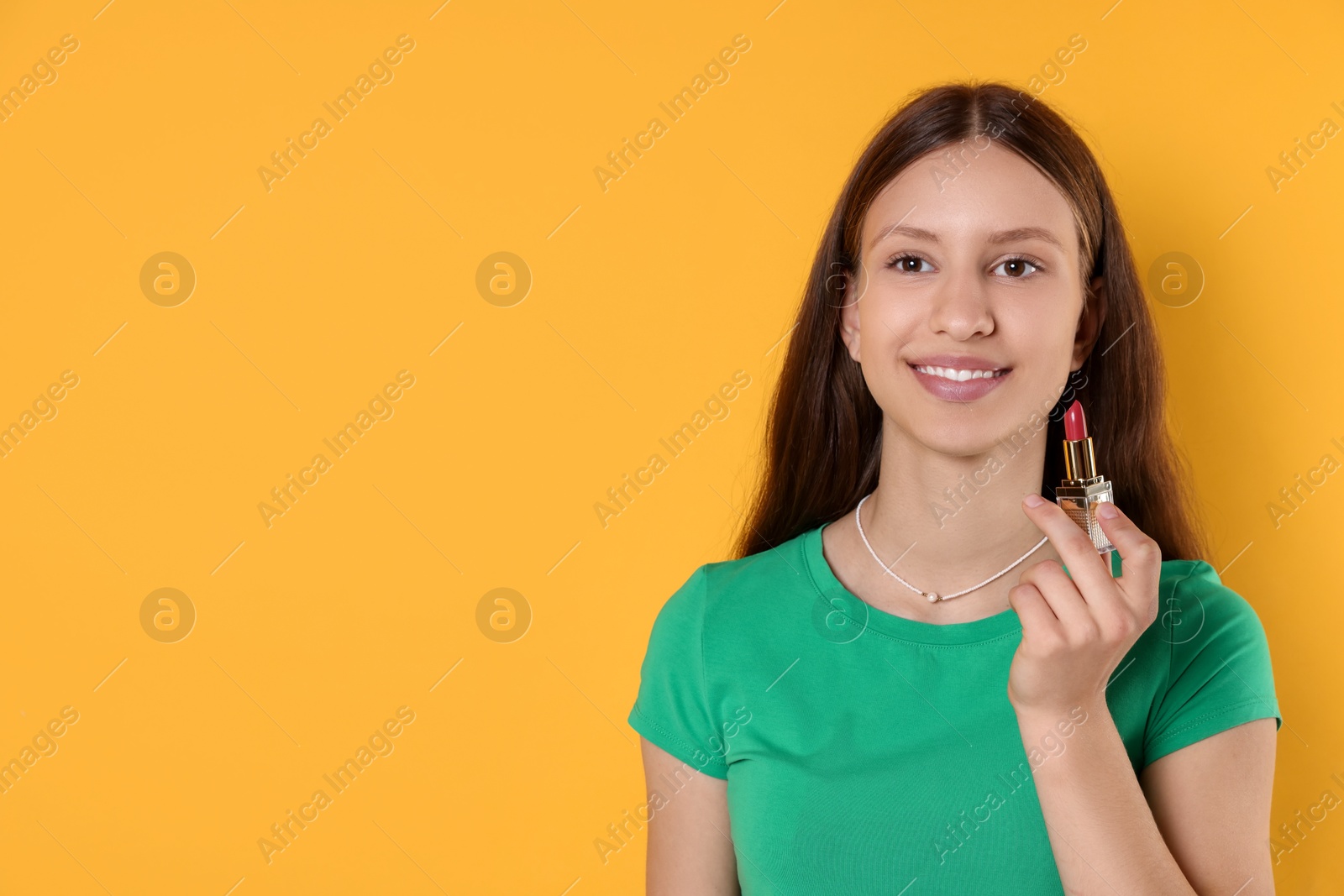 Photo of Smiling teenage girl with lipstick on yellow background. Space for text