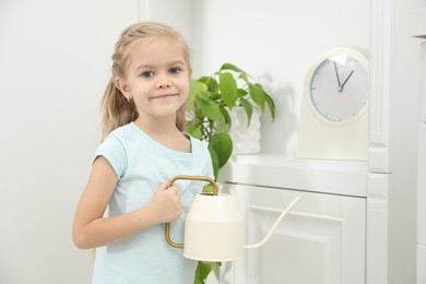 Photo of Little helper. Cute girl with watering can at home