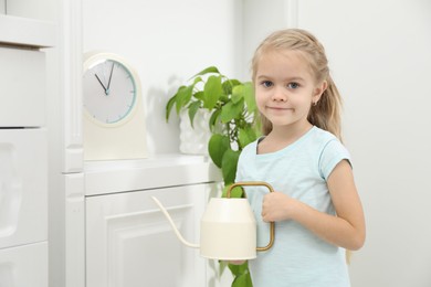 Photo of Little helper. Cute girl with watering can at home