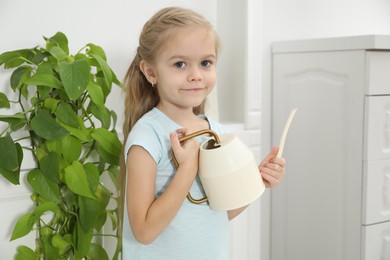 Photo of Little helper. Cute girl with watering can at home