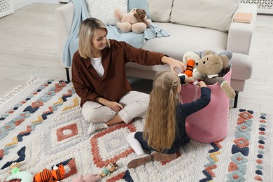 Photo of Little helper. Daughter and mother putting away toys together at home