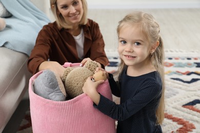 Little helper. Daughter and mother putting away toys together at home, closeup