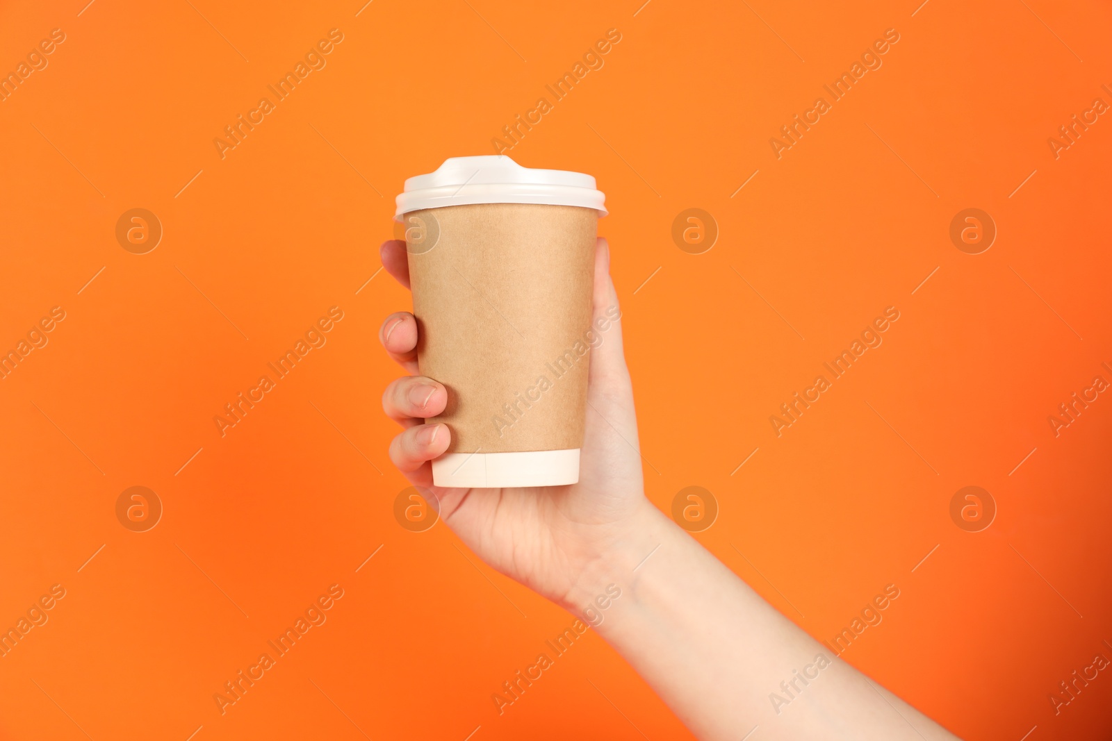 Photo of Woman holding paper cup on orange background, closeup. Mockup for design