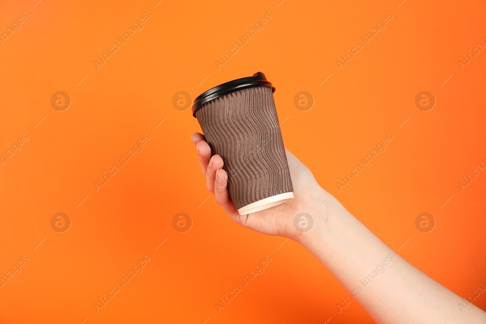 Photo of Woman holding paper cup on orange background, closeup. Mockup for design