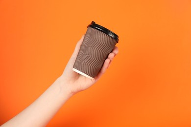 Photo of Woman holding paper cup on orange background, closeup. Mockup for design