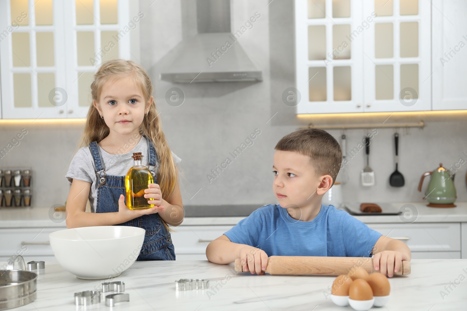 Photo of Little helpers. Children making dough for cookies in kitchen at home