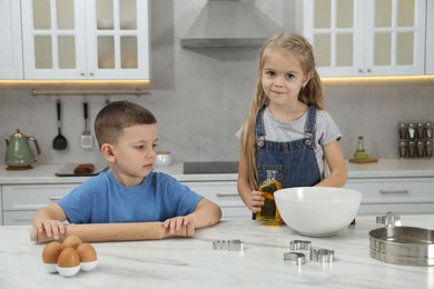 Photo of Little helpers. Children making dough for cookies in kitchen at home