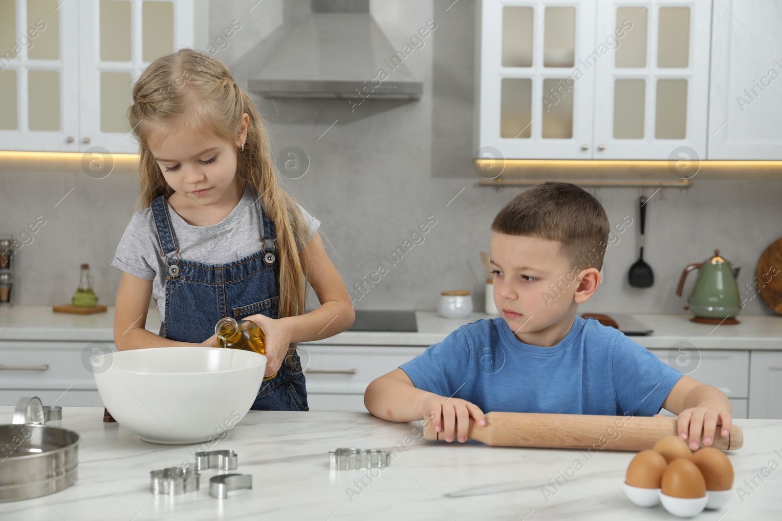 Photo of Little helpers. Children making dough for cookies in kitchen at home