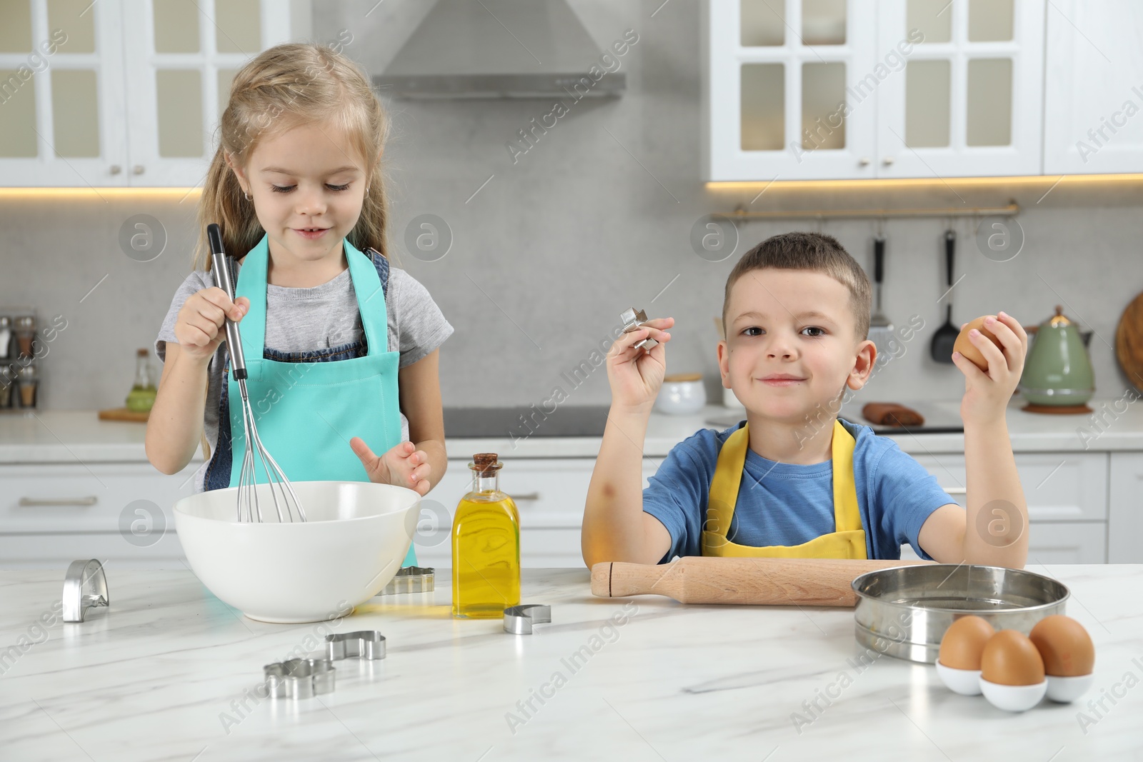 Photo of Little helpers. Children making dough for cookies in kitchen at home