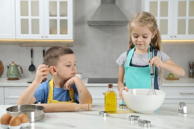 Little helpers. Children making dough for cookies in kitchen at home