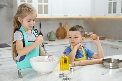 Photo of Little helpers. Children making dough for cookies in kitchen at home