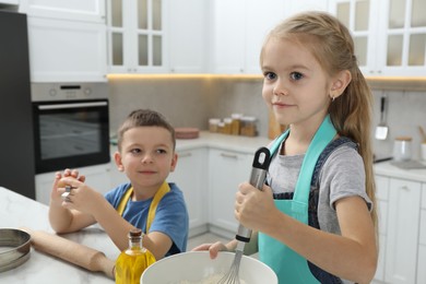 Photo of Little helpers. Children making dough for cookies in kitchen at home