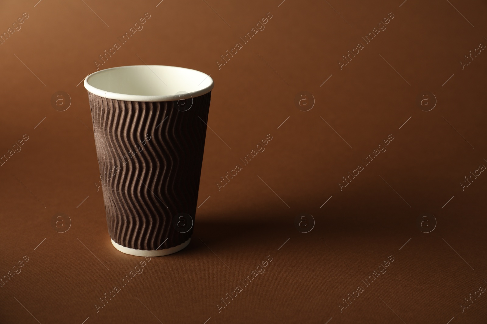 Photo of One paper cup on brown background. Mockup for design