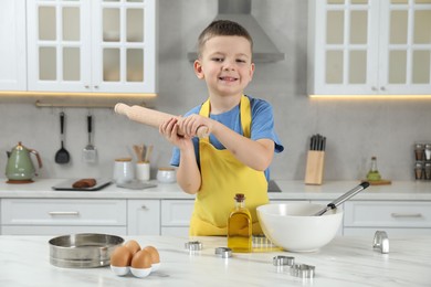 Photo of Little helper. Cute boy making dough for cookies in kitchen at home