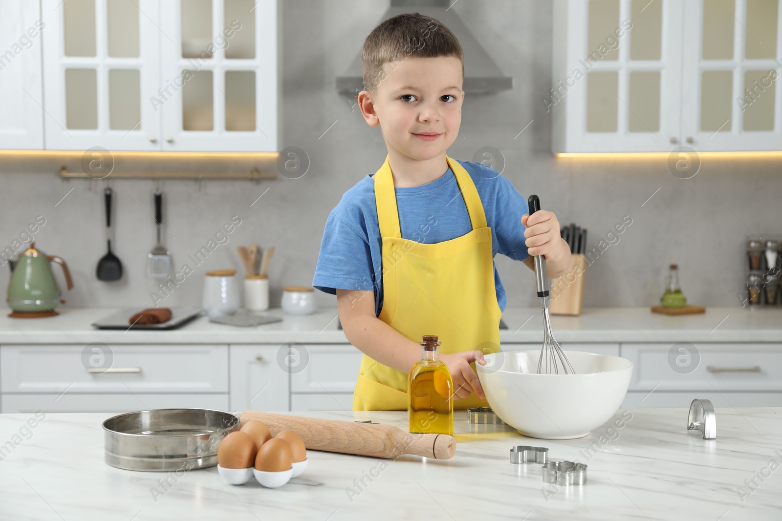 Photo of Little helper. Cute boy making dough for cookies in kitchen at home